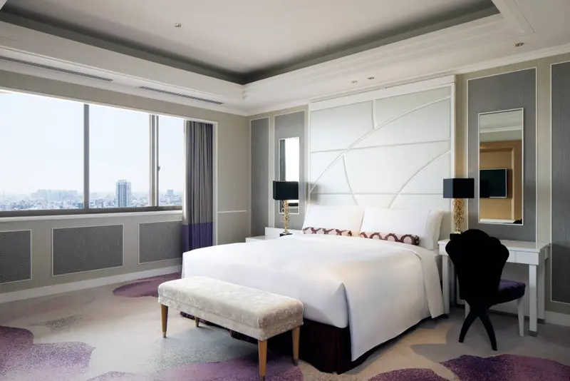 Une chambre lumineuse avec un grand lit et une vue sur la ville.