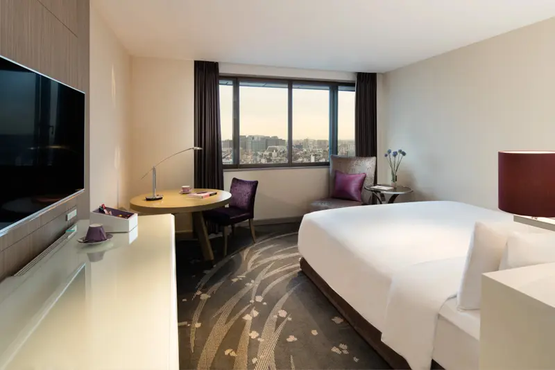 Une chambre lumineuse avec un lit et un coin repas près d'une fenêtre.