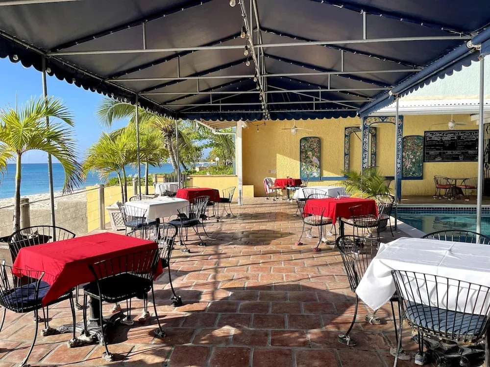 Terrasse ombragée avec tables et chaises donnant sur la mer.