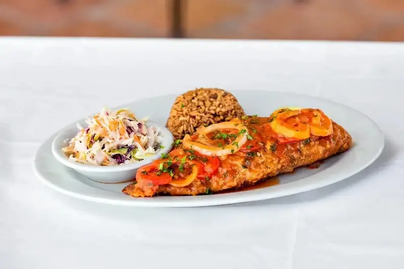 Assiette de poisson pané servi avec du riz et une salade de chou.