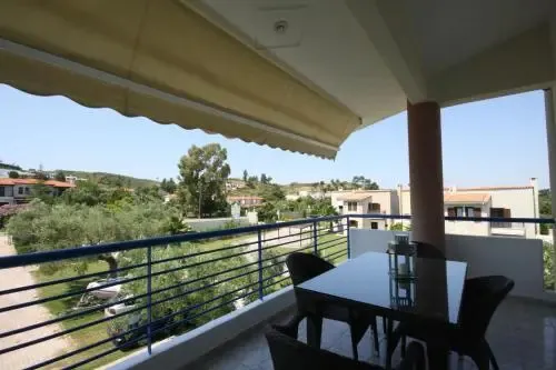 Une terrasse ombragée offre une vue sur un paysage verdoyant et des bâtiments.