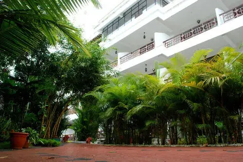 Un bâtiment blanc à plusieurs étages est entouré d'une végétation luxuriante.