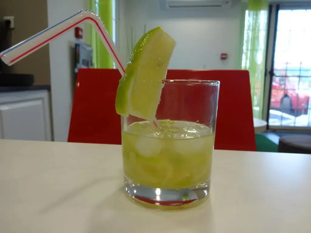Un verre de boisson fraîche décoré d'une tranche de citron vert et d'une paille.