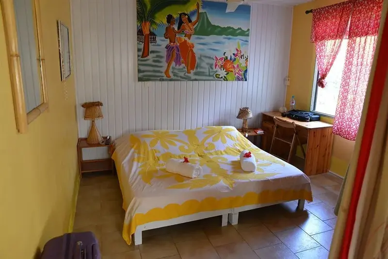 Une chambre lumineuse avec un grand lit décoré de fleurs et une peinture murale colorée.