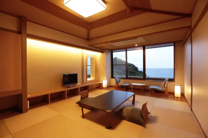 Une pièce lumineuse avec une vue sur la mer à travers de grandes fenêtres.