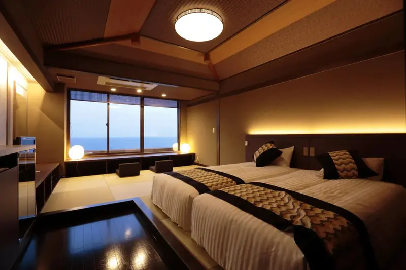 Une chambre lumineuse avec deux lits simples et une grande fenêtre donnant sur la mer.