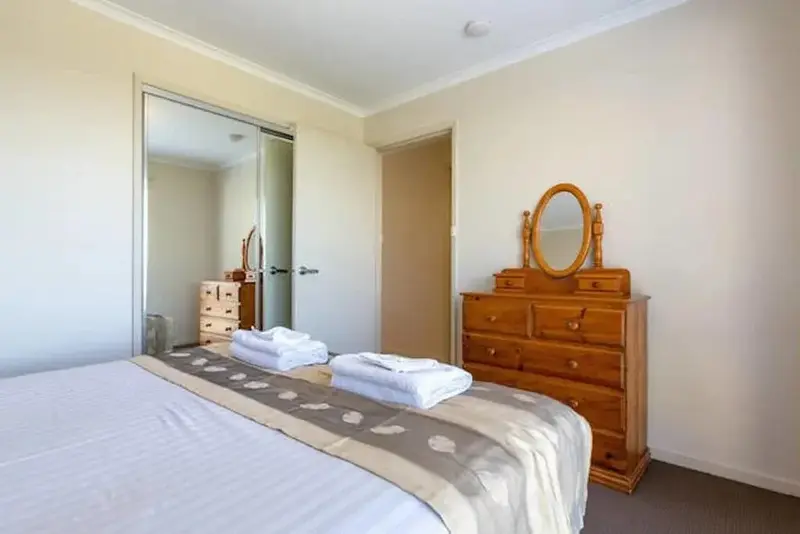Une chambre lumineuse avec un grand lit et une commode en bois.