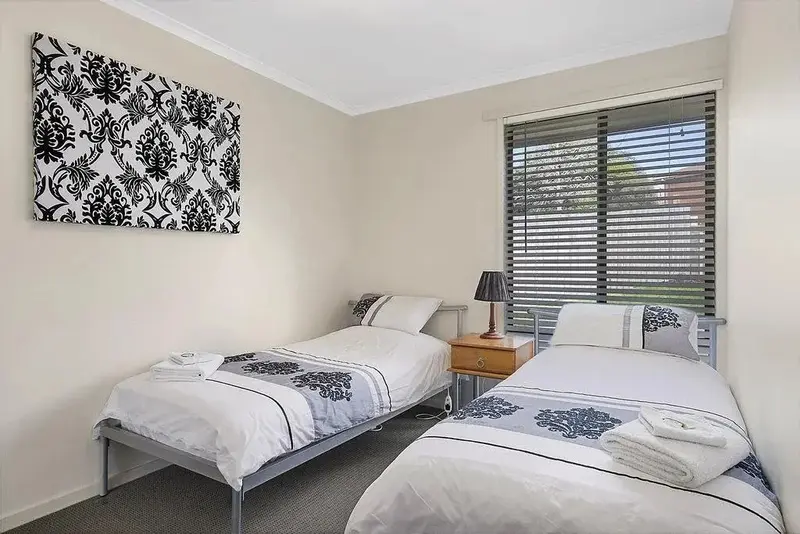 Une chambre lumineuse avec deux lits simples et une décoration sobre.