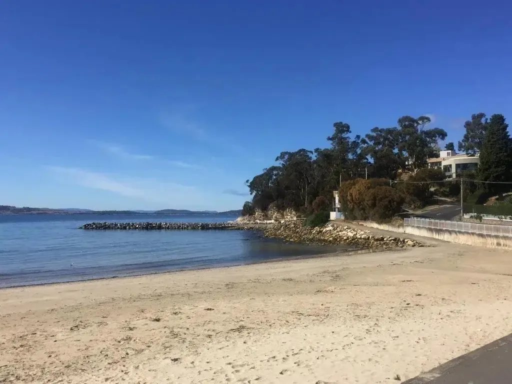 Une plage de sable fin borde une eau calme sous un ciel bleu dégagé.