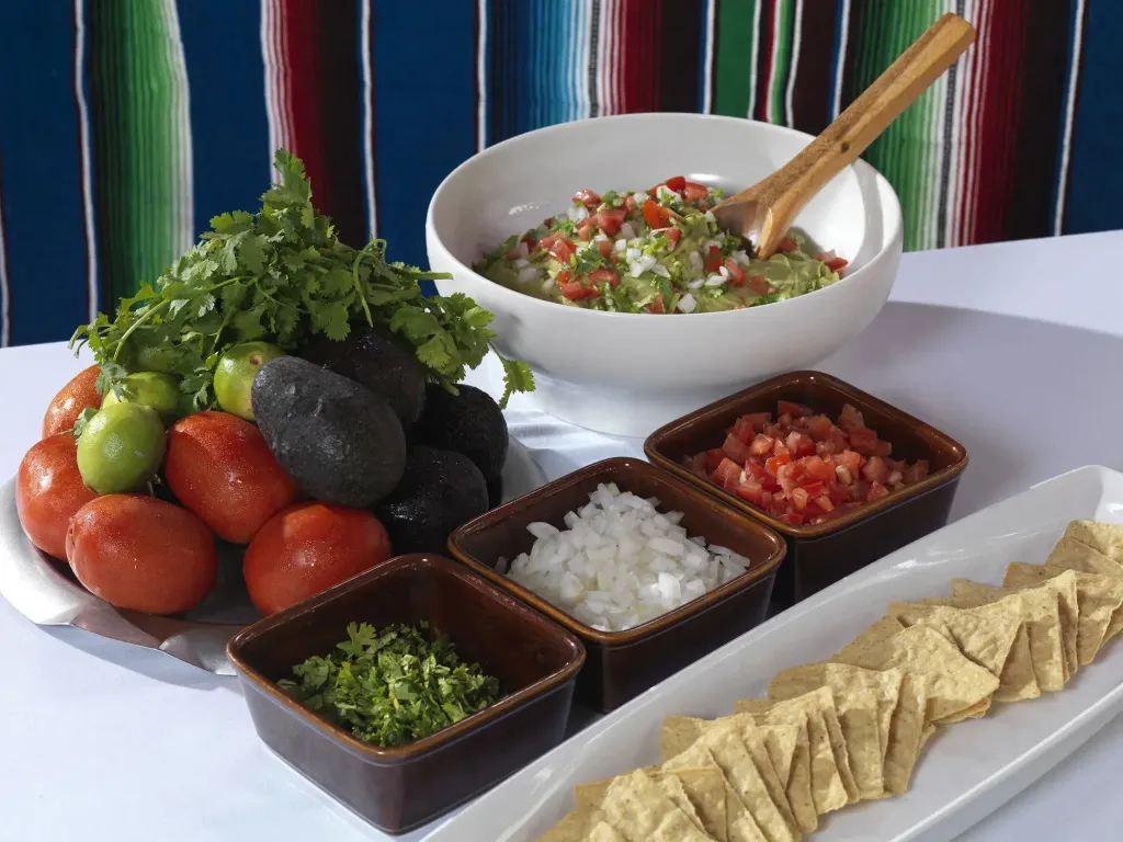 Assortiment de légumes frais, guacamole et chips de tortillas sur une table.