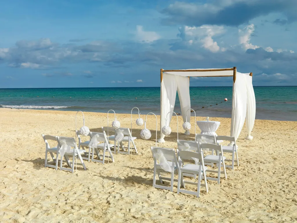 Une arche fleurie est dressée sur une plage de sable fin face à la mer turquoise.