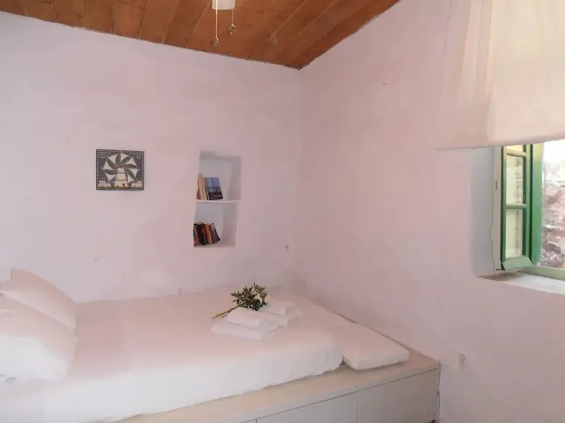Une chambre lumineuse avec un lit simple et une fenêtre ouverte.