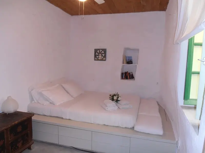 Une chambre lumineuse avec un lit intégré et des étagères murales.