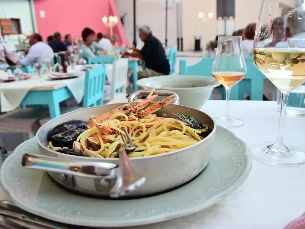 Un plat de pâtes aux fruits de mer est présenté sur une table en terrasse.