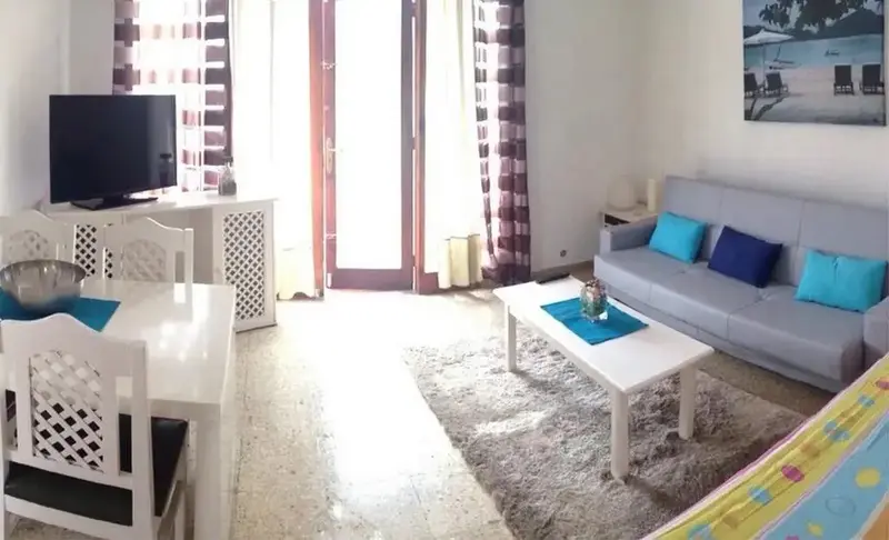 Espace de vie lumineux avec canapé, table basse et coin repas.