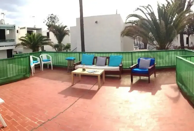 Terrasse carrelée avec mobilier de jardin et végétation tropicale.