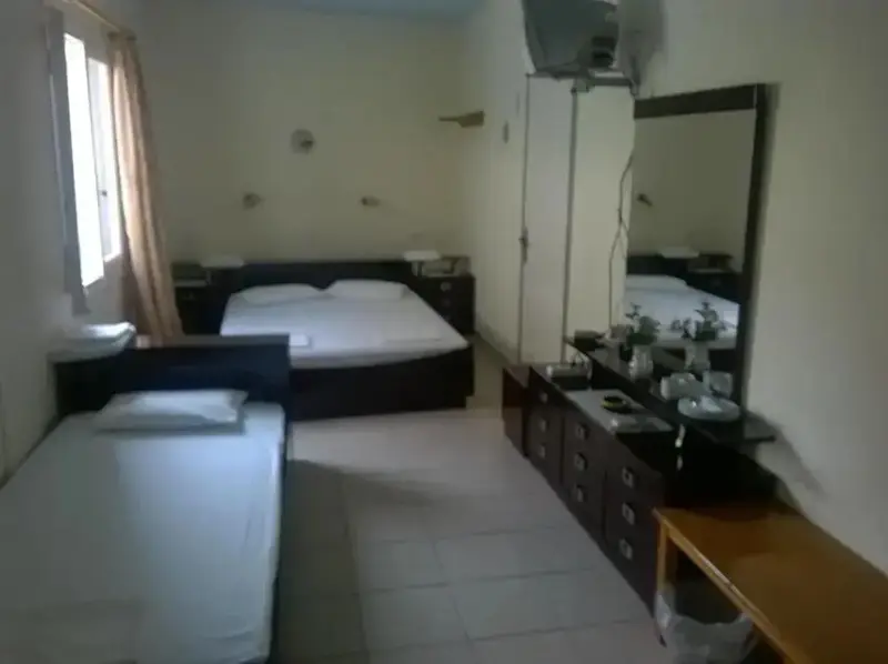 Une chambre lumineuse avec lits simples et commode.