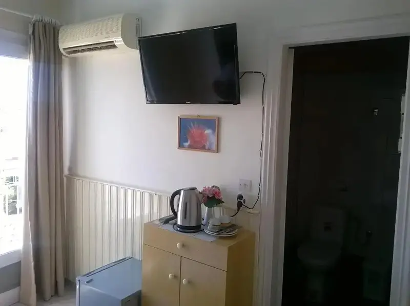 Une bouilloire et une télévision sont posées sur une commode dans une chambre.