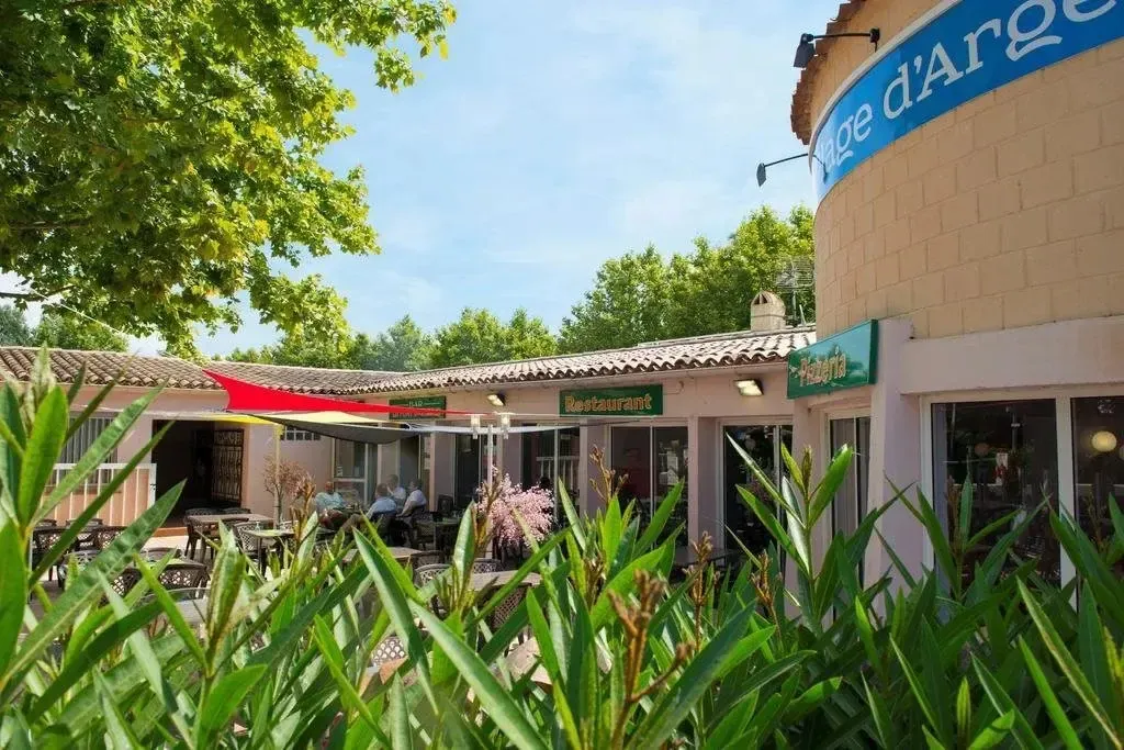 Terrasse ombragée avec tables et chaises devant un restaurant.