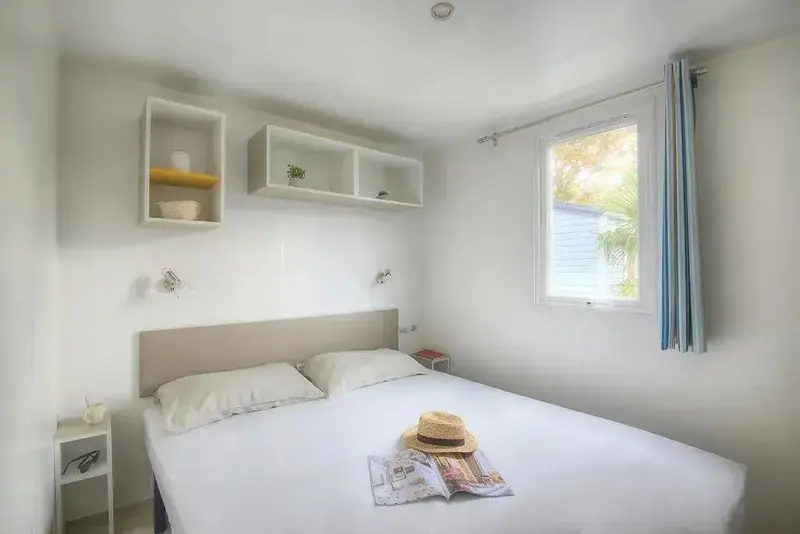 Une chambre lumineuse avec un lit double et des étagères murales.