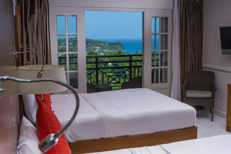 Une chambre lumineuse avec vue sur la mer et la végétation.
