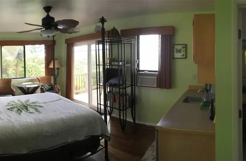 Une chambre lumineuse avec un lit recouvert d'une courtepointe et un accès à une terrasse.