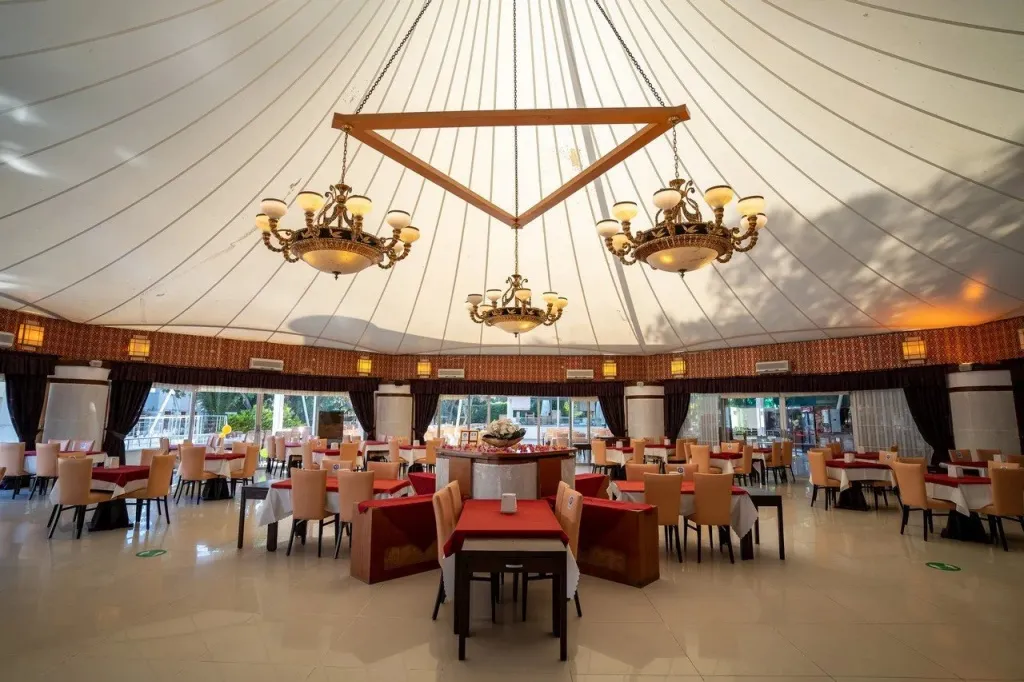 Une salle de restaurant lumineuse avec des tables dressées et des lustres.