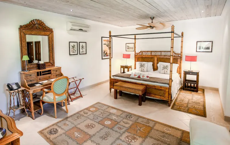 Une chambre lumineuse avec un grand lit à baldaquin et un bureau en bois.