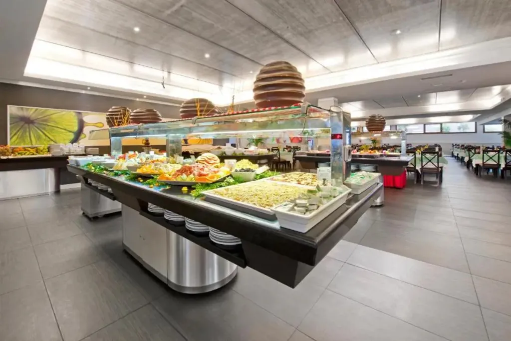 Un buffet propose une variété de plats frais et colorés dans une salle lumineuse.