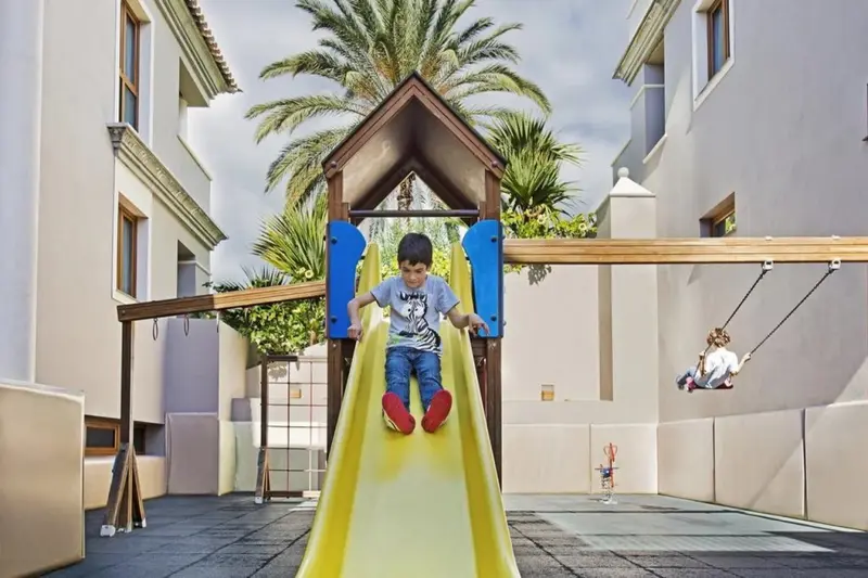 Un enfant descend d'un toboggan sur une aire de jeux en plein air.