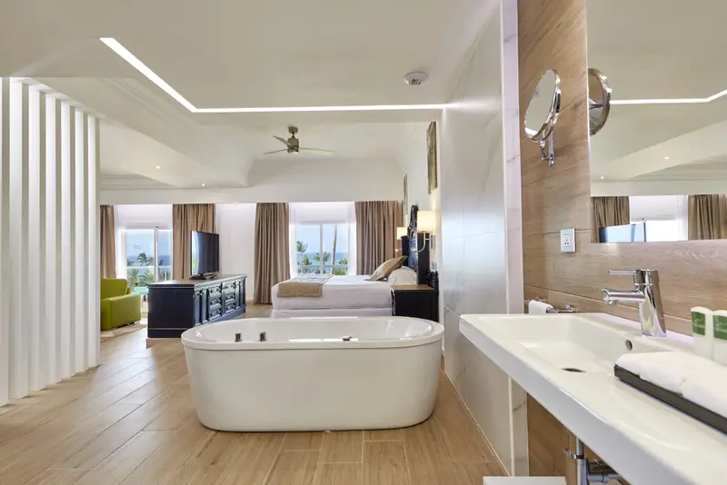 Une grande chambre lumineuse avec baignoire et salle de bain attenante.