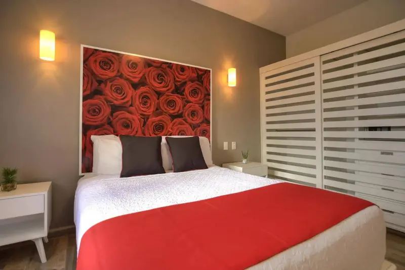 Une chambre moderne avec un grand lit recouvert d'une courtepointe rouge et d'oreillers décoratifs.