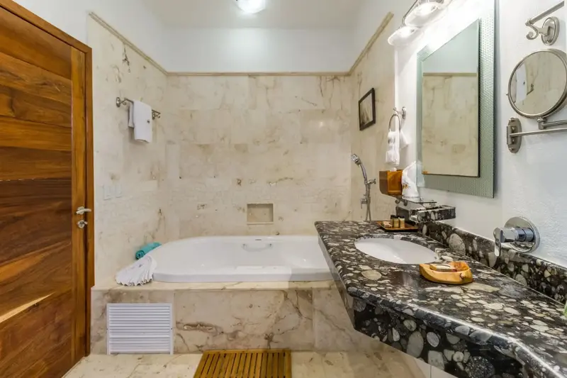 Une salle de bain lumineuse avec baignoire et vasque en marbre.