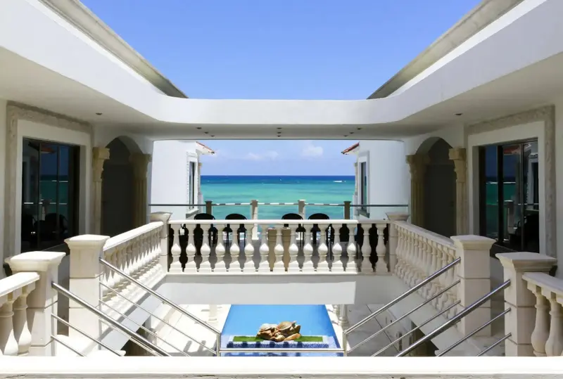 Balcon avec vue sur la mer turquoise et une fontaine décorative.