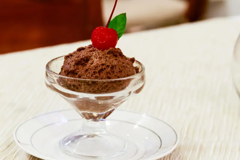 Une coupe de glace au chocolat est garnie d'une cerise.