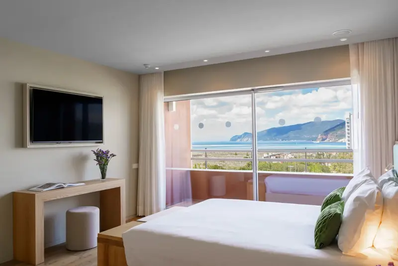 Une chambre lumineuse avec un grand lit donnant sur une vue mer.