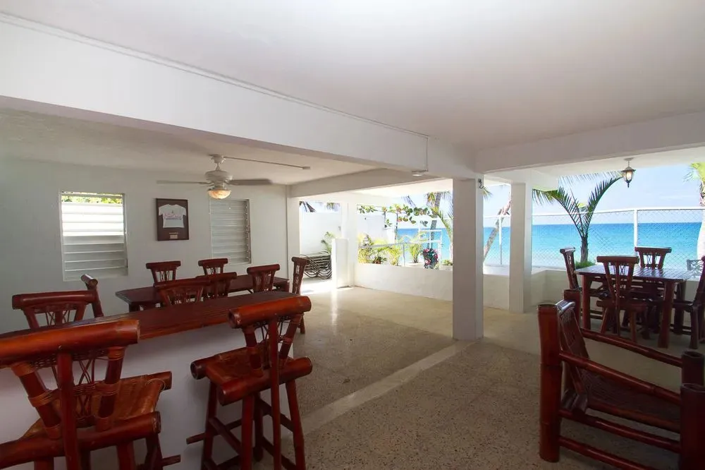 Une salle lumineuse s'ouvre sur une vue sur la mer et une végétation tropicale.