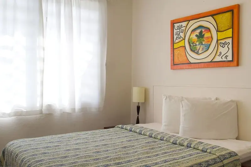 Une chambre lumineuse avec un lit recouvert d'une courtepointe et une décoration murale colorée.