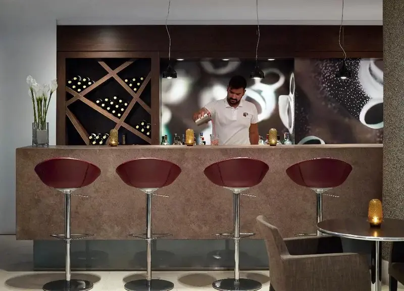Un barman prépare un cocktail derrière un comptoir moderne.