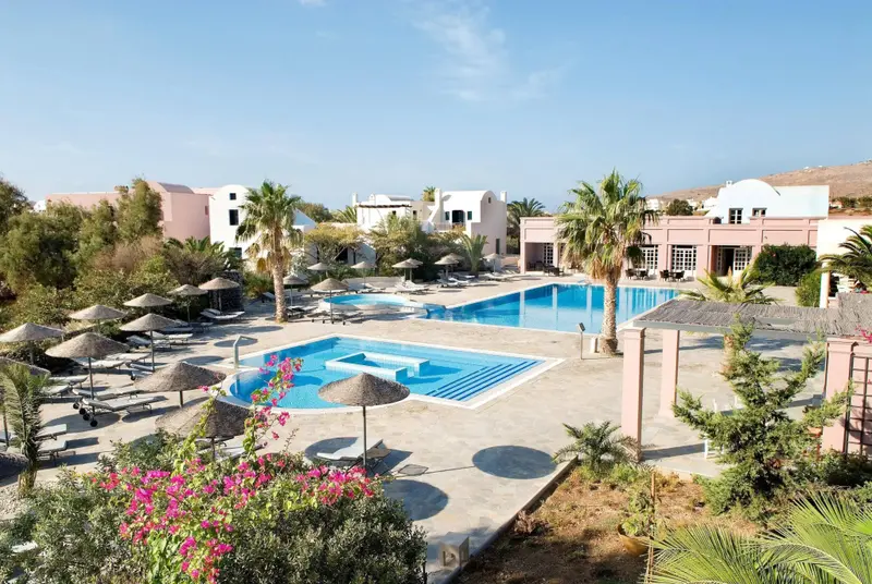 Vue aérienne d'une piscine avec des parasols et des transats dans un complexe hôtelier.