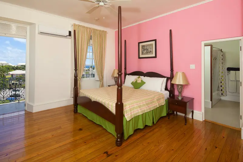 Une chambre lumineuse avec un grand lit à baldaquin et un mur rose.
