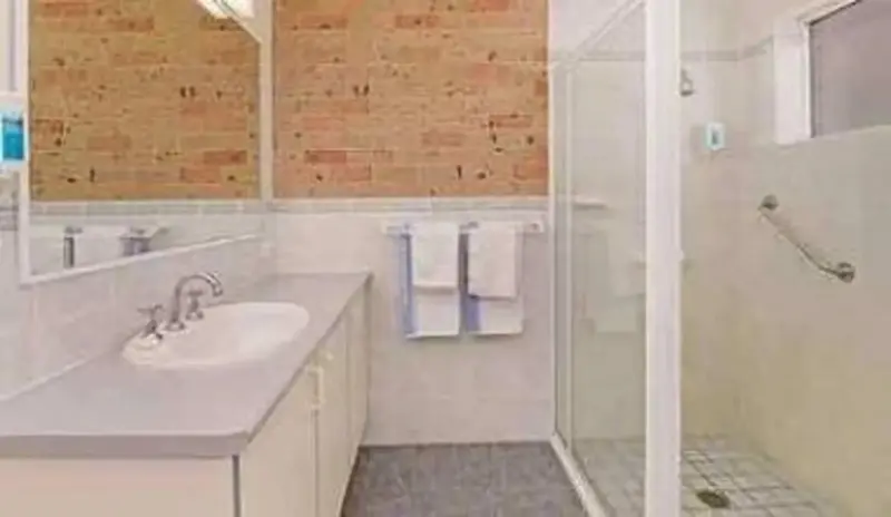 Une salle de bain claire avec douche et lavabo.