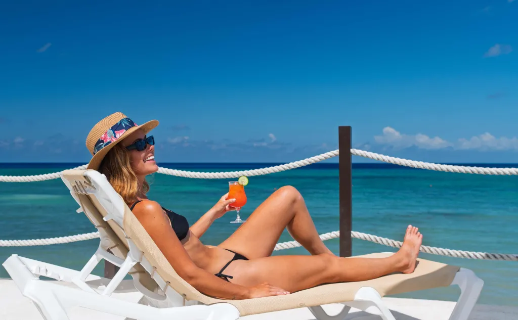 Une femme se détend sur un transat face à la mer turquoise.