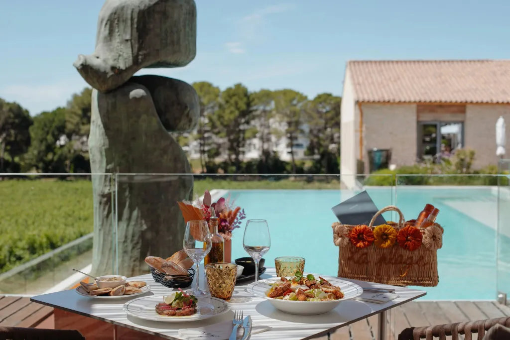 Une table est dressée avec des plats et des boissons au bord d'une piscine.