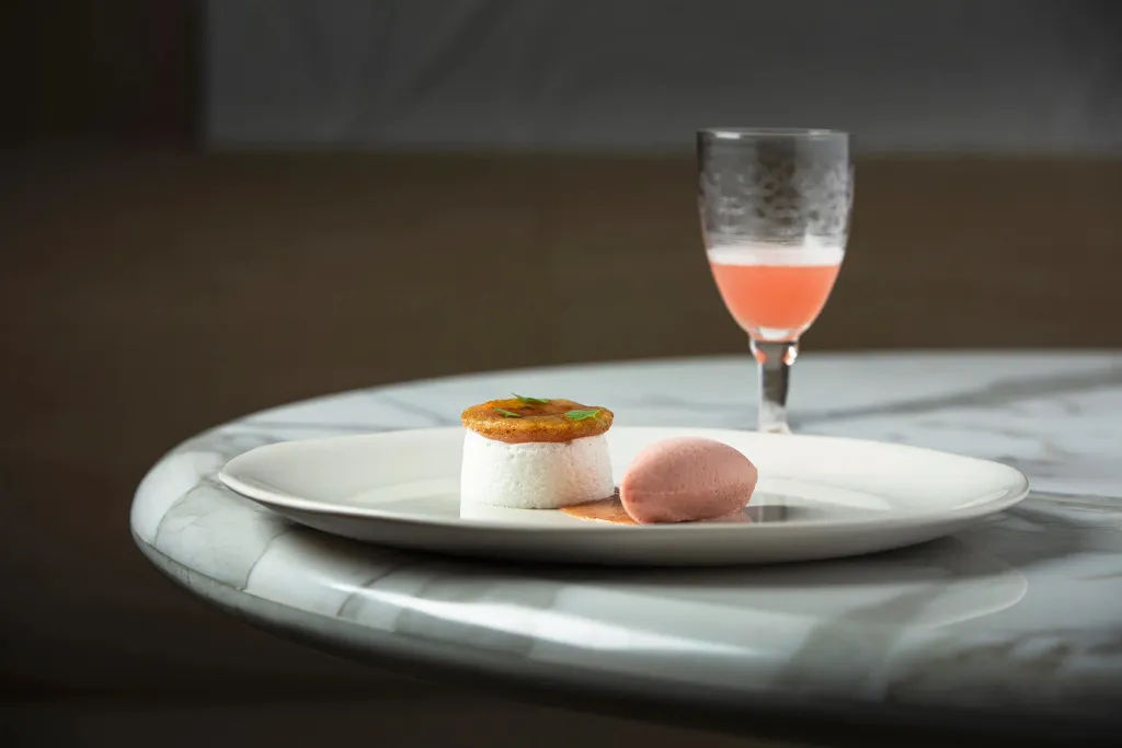 Assiette raffinée avec une préparation culinaire et une boisson rosée.