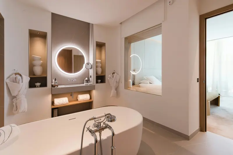 Une baignoire blanche est au centre d'une salle de bain lumineuse et moderne.