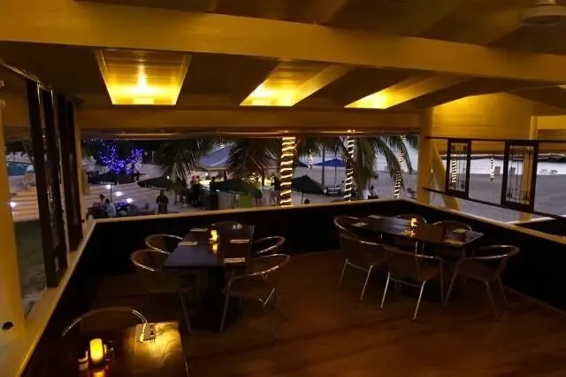 Une salle à manger lumineuse s'ouvre sur une promenade bordée de palmiers.