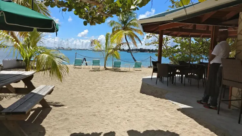 Une plage de sable clair avec des tables et des chaises, face à la mer.