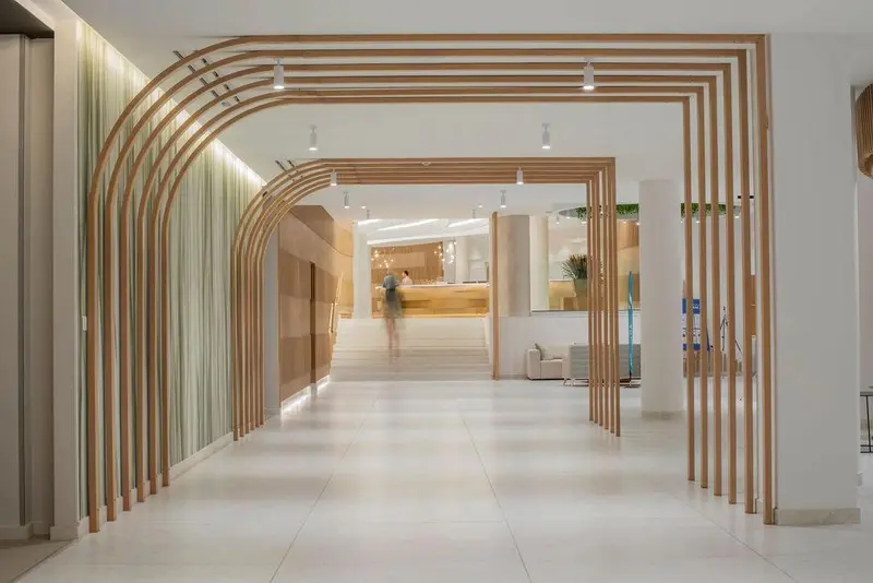 Hall d'entrée lumineux avec un décor en bois et un comptoir d'accueil en fond.
