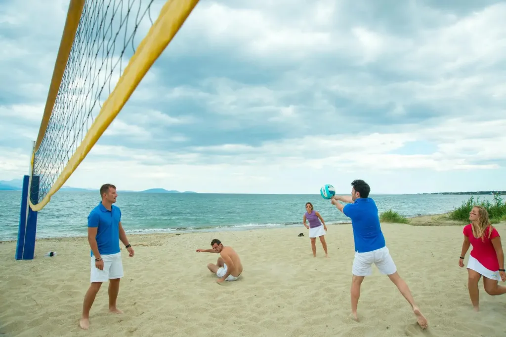 Des personnes jouent au volley-ball sur une plage de sable fin face à la mer.